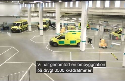 Rymligt stort garage för ambulanser där två män samtalar